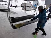 De stoel wordt bij het instappen met een bezem van sneeuw geveegd.